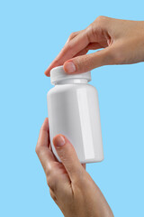 Hands female showing medical plastic bottle mockup as soft-gel capsules pour out. Medicine advertising mockup. Showcasing vitamins, dietary supplements, and nutrition products. 