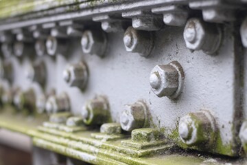 Steel construction detail with old mossy screws on bridge railing.