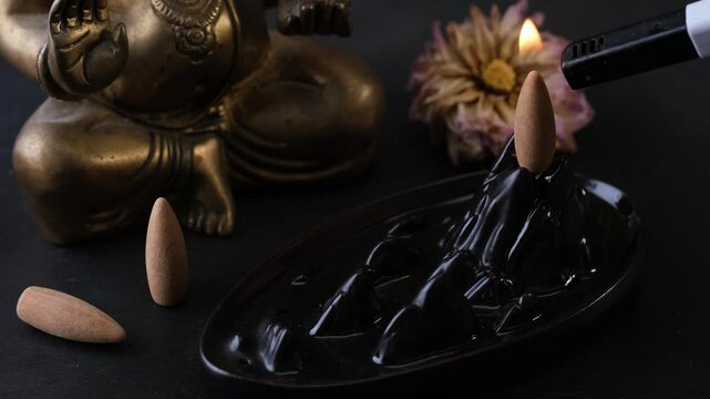 Ceramic backflow incense holder with smoldering incense cone on top, producing the impression of a captivating waterfall effect. Timelapse, lockdown shot.