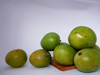 A number of ripe mangoes on a wooden cutting board on a white background, ready to be enjoyed