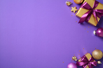 Festive holiday decorations on purple background for vibrant seasonal design use. Flat lay golden and purple Christmas baubles, star-shaped decorations, and a gift boxes with a purple bows