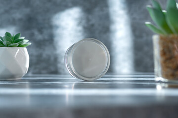 clear cream jar on the grey surface with overlay shadow, use for beauty mockup product