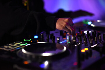 A DJ adjust audio mixing knobs on a vibrant console to creating an electric fun sound atmosphere....