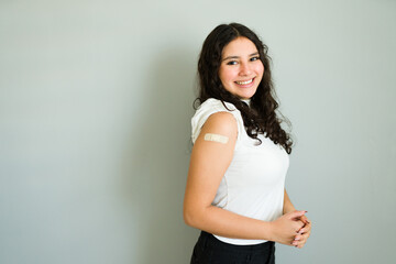 Happy teenager proudly displays bandaged arm after receiving vaccination