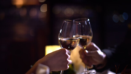 Clinking Glasses with White Wine in a Dimly Lit Atmosphere