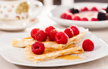Breakfast of pancakes with fresh raspberries on table
