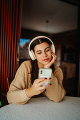 Young caucasian woman enjoying music on wireless headphones at home	