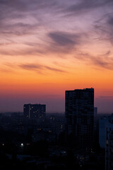 Fototapeta premium Silhouettes of urban buildings during sunset with dramatic clouds. Evening cityscape photography