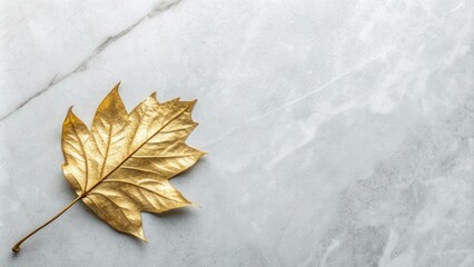 A single golden leaf rests upon a smooth white marble surface, its delicate veins and intricate structure illuminated by the soft light.
