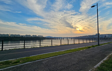 서울의 한강에서 노을지는 하늘과 불빛이 반짝이는 교량이 있는 도시 경관