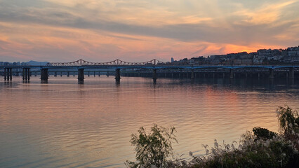 Fototapeta premium 서울의 한강에서 노을지는 하늘과 불빛이 반짝이는 교량이 있는 도시 경관