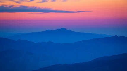 Obraz premium Majestic twilight view of layered mountains with colorful sky during sunset in a serene landscape