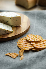a blue cheese with some cookies on a table.