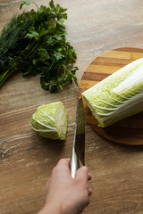 a woman prepares a salad of Chinese cabbage and fresh herbs in the kitchen. top view