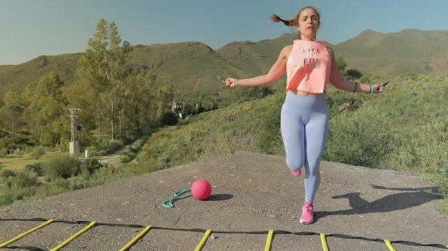 Fit Woman Jumps Rope Doing Sport in Nature with Mountains in the Background. Mujer Fitness Salta a la Comba Haciendo Deporte en la Naturaleza con Monta&ntilde;as de Fondo
