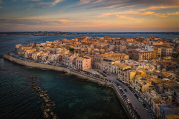 Fototapeta premium Siracusa, Ortigia Island from the air at sunset, Sicily, Italy. Isola di Ortigia, coast of Ortigia island at city of Syracuse, Sicily, Italy. Aerial view. June 2023