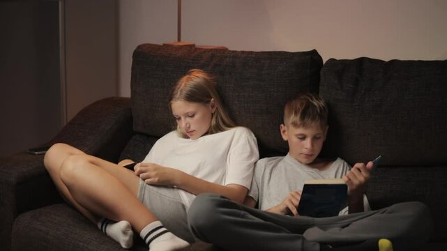 boy and girl sitting on a couch they play games with phones