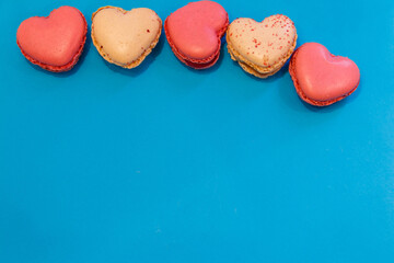 Sweet heart shaped macaroons on blue background. Top view, copy space. Valentine Day concept
