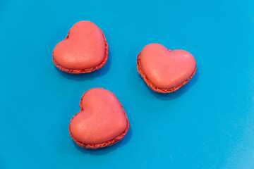 Sweet heart shaped macaroons on blue background. Top view. Valentine Day concept
