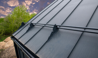 Snow rails are installed on gray seam roof © Sergey