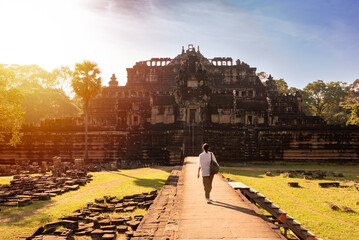 Naklejka premium Traveller walking to Angkor ancient temple ruins in Cambodia