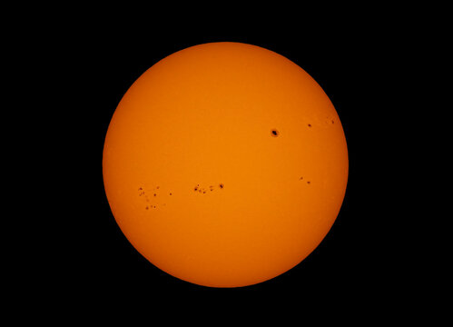 The orange coloured afternoon sun glowing with many large sunspots against a black background on November 6, 2024 Canada