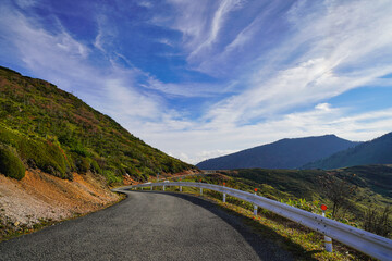 晴天の青空と山間のカーブした道
