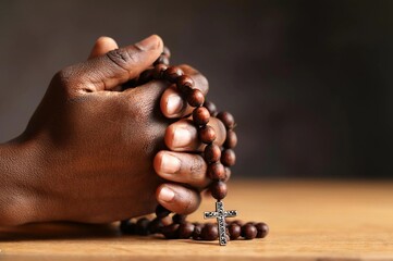 Man's hands pray to hold a bead rosary with Jesus Christ on the cross or the Crucifix. Christian Catholic religious faith holding a black rosary and praying.

