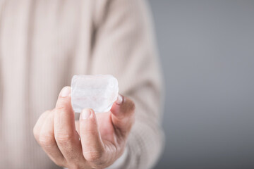 Man holding an ice cube, with a look of discomfort due to the cold, highlighting the sensitivity...