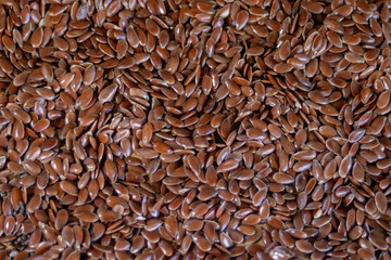 Pile of brown flax seeds scattered for background of healthy seeds promotion.