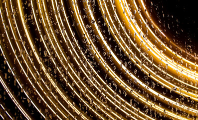 A long exposure photograph. Light painting photography - vibrant gold fairy lights behind a wet...
