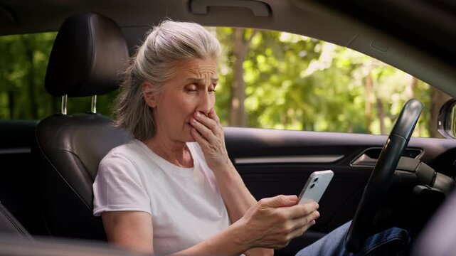 Shocked upset scared Caucasian elderly aged woman female car driver client user holding mobile phone smartphone shock receiving bad news cellphone scam app error trouble upset worry inside automobile