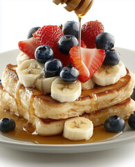French toast with blueberries, strawberries, and banana slices on top, drizzled in honey or syrup. 