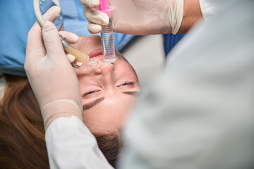 Doctor performs nasal procedure on lying patient