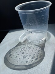 empty cup of water on airplane tray table with water drops shadows
