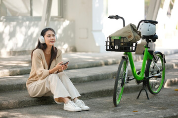 Obraz premium A woman is sitting on a set of stairs with a green bicycle next to her