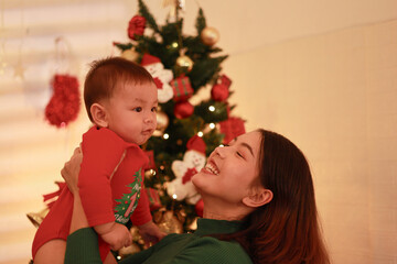 Mother and son playing together on Christmas Eve. Happy family. Mother and little son. Christmas tree. Family holiday.