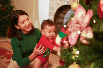 Mother and son playing together on Christmas Eve. Happy family. Mother and little son. Christmas tree. Family holiday.