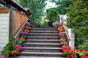 A beautiful stone staircase surrounded by flowers in pots and a golden openwork bench.