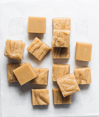 Overhead view of peanut butter fudge on a white marble tray, top view of soft peanut fudge squares on a white background