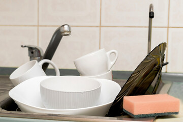 Kitchen sink filled unwashed dirty dishes,utensils need washing after lunch,dinner.lack of time,home routine,chores.dishwashing gel liquid bottle soap dispenser,counter.hygiene,protective home.