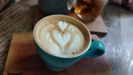 A cup of hot coffee with latte art on the wooden tray
