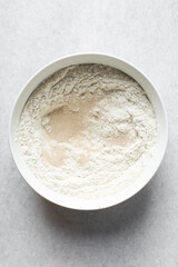 Overhead view of ingredients for making puff-puff in a white ceramic bowl, yeast flour sugar in a mixing bowl, process of making puff-puff