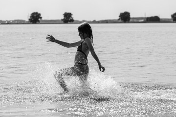 Beautiful girl playing on the pond in summer. Black and white photo.