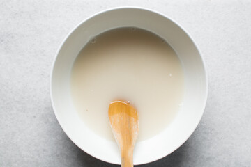 Overhead view of Instant dry yeast sprinkled on warm water, top view of dry yeast granules dissolved in water