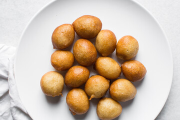 Overhead view of nigerian puff-puff on a white plate, nigerian fried dough balls, flatlay of...