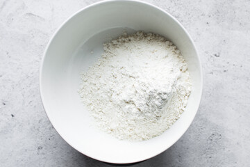 overhead view of All purpose flour in a bowl, top view of baking flour in a ceramic bowl