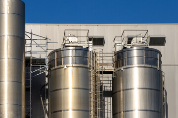 Industrial silos gleaming under a clear blue sky at a modern processing plant