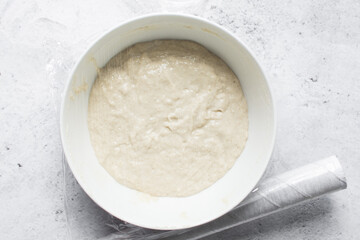 Overhead view of nigerian puff-puff dough that has proofed, puff-puff dough in a white mixing bowl, process of making puff-puff or bofrot