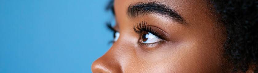 Obraz premium A close-up of an eye with a vibrant blue background, showcasing clear lashes and healthy skin texture.